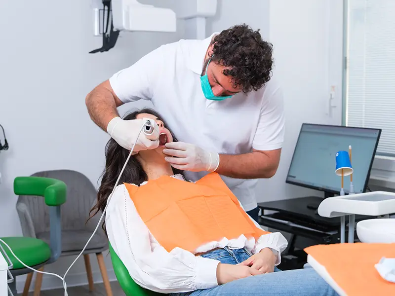 Dottore che esegue lo scanner intraorale ad una paziente