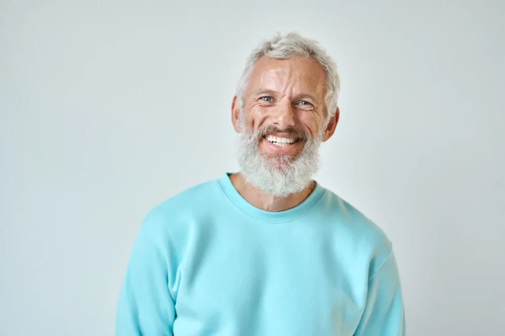 Uomo con barba bianca e maglia celeste che sorride